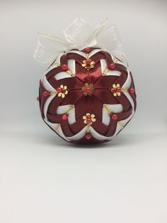 a red and white ornament with flowers on it's side is shown