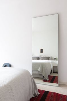 a bedroom with a large mirror on the wall and a bed in front of it