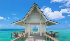 a wooden dock leading to a white house on the ocean