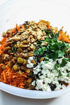 a bowl filled with carrots, feta cheese and nuts