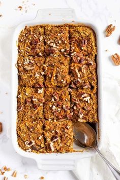 a casserole dish filled with granola and pecans on a white surface