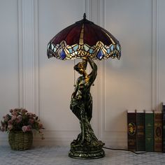 a lamp that is on top of a table next to some books and a basket