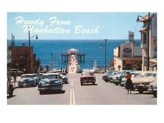 an old photo of cars driving down the road by the ocean with a pier in the background