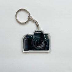 a camera keychain is shown on a white surface