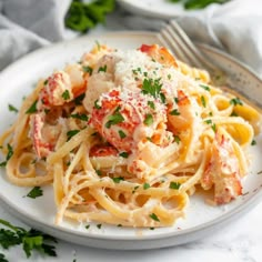 pasta with lobster and parmesan cheese on a white plate next to a fork