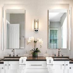 a bathroom with two sinks, mirrors and lights on the wall above them is shown