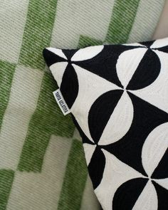 a black and white pillow sitting on top of a green chair next to a wall