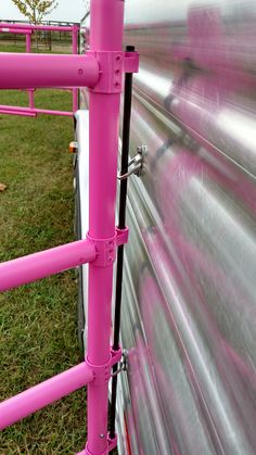 pink pipes are attached to the side of a metal structure in an open grassy area