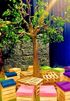 a tree that is sitting in the middle of some wooden pallet tables and chairs