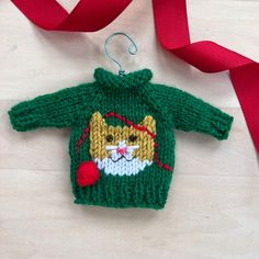 a knitted cat ornament hanging from a red ribbon