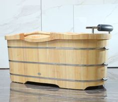 a large wooden tub sitting on top of a marble floor next to a faucet