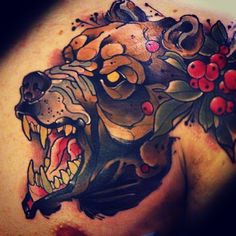 a tattoo on the back of a man's shoulder with a bear and berries