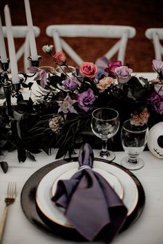 the table is set with purple and black flowers, candles, and skulls on it