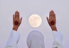 two hands reaching up to the sky with a full moon in the background