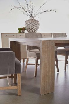 a wooden table with chairs around it and a vase on top of the dining room table