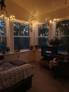 a bed room with a neatly made bed and a flat screen tv sitting on top of a wooden floor