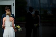 a bride and groom standing in front of a glass door