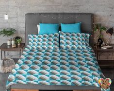 a bed with blue and white bedspread in a room next to two tables