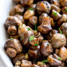 cooked mushrooms in a white dish with parsley on the top, ready to be eaten