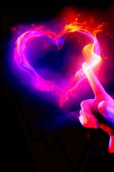 a person holding a heart shaped object in their hand with flames coming out of it