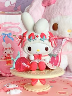 a hello kitty doll sitting on top of a table next to a stuffed animal rabbit