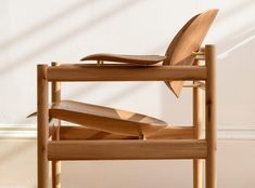 a stack of wooden chairs sitting on top of a white floor next to a wall