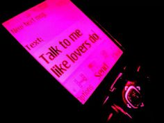 a pink sign that says talk to time like lovers do on a black cell phone