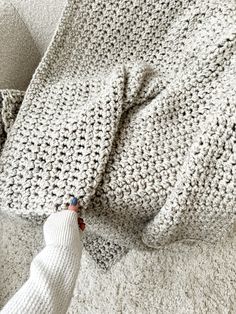 a white knitted blanket laying on top of a bed