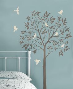 a bedroom with a tree and birds painted on the wall