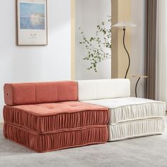 an orange and white couch sitting on top of a carpeted floor next to a window