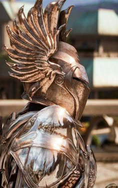 a close up of a metal statue with a bird on it's head and wings