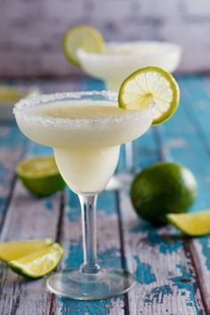 two margaritas with lime slices and sugar on the rim, sitting next to each other