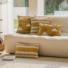 a living room filled with lots of pillows on top of a couch next to a window