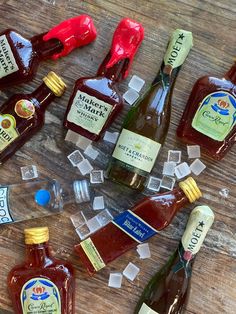 many different types of condiments and bottles on a wooden table with ice cubes