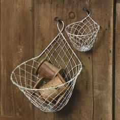 two wire baskets with wooden spoons hanging from the side on a wood wall next to each other