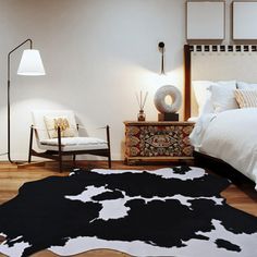 a bed room with a neatly made bed and a cow skin rug on the floor