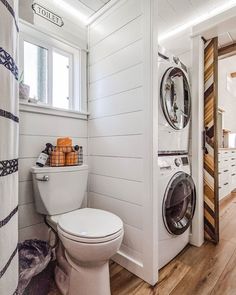 a white toilet sitting next to a washer and dryer inside of a bathroom