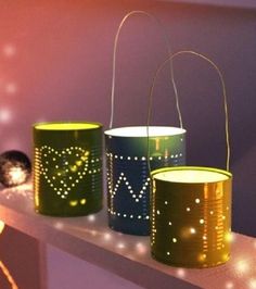 three tin can lights sitting on top of a shelf next to some string lights and balls