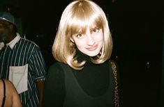 a woman with blonde hair and bangs standing next to a man in a black shirt