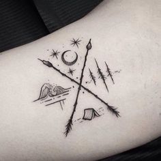 the back of a woman's shoulder with an arrow and compass tattoo on it