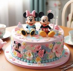 a birthday cake decorated with mickey and minnie mouse figurines