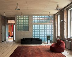 a living room filled with furniture and windows next to a red rug on top of a hard wood floor