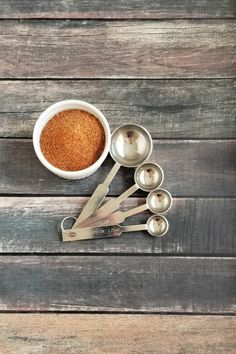 measuring spoons and measuring cups with spices in them on a wooden table top next to measuring spoons