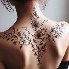 the back of a woman's neck with flowers and leaves tattooed on her chest