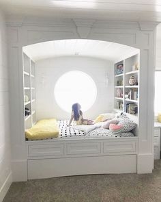 a woman sitting on top of a bed under a window