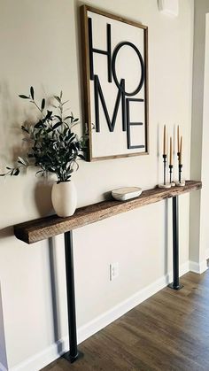 a long wooden table with candles on it in front of a framed art piece that says home