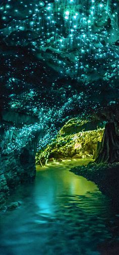 the inside of a cave is lit up with green lights and water running through it