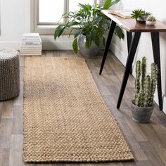 a living room with wooden floors and a rug on the floor next to a window