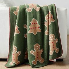 a green blanket with gingerbreads on it sitting next to a white couch in a living room