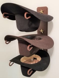 three hats are stacked on top of each other in front of a wall mounted hat rack